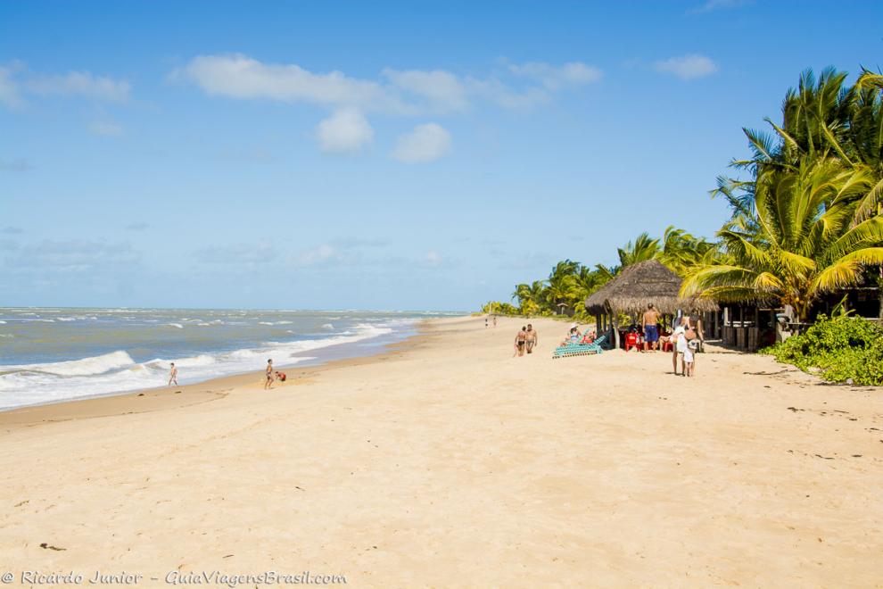 Imagem de turistas e quiosques na Praia Guaiú.